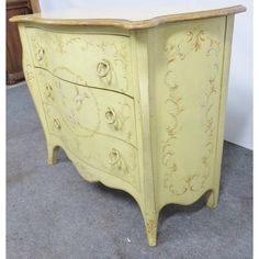 an old yellow painted chest of drawers with ornate designs on the top and bottom drawer