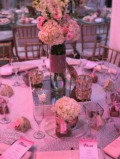 a table set with pink and white flowers in vases, napkins and place cards