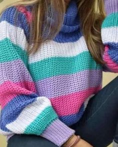 a woman is wearing a colorful sweater and jeans