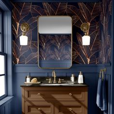 a bathroom with blue walls, gold fixtures and palm leaf wallpaper on the wall