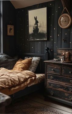 a bedroom with black walls and wooden flooring has a bed, dresser, and painting on the wall