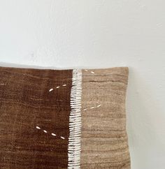 a brown and white pillow sitting on top of a wooden floor next to a wall