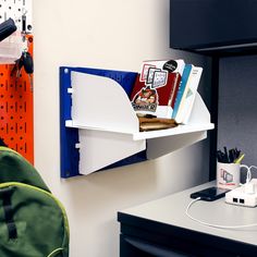 a desk with some books on it and a backpack hanging from the wall next to it