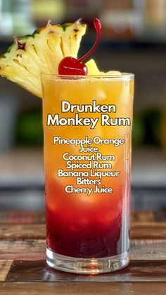 a drink in a tall glass with a cherry and pineapple garnish on the rim