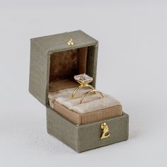 Introducing the Georgian Ring Box, a stunning homage to the classic Georgian design. Inspired by tradition, this square-shaped beauty features an exterior crafted from fine linen, exuding timeless elegance. Open it to reveal a luxurious velvet cushion, meticulously designed to put all of the attention on your ring. Choose single or double slot.  Completed with a delicate metal clasp, this heirloom-worthy ring box adds a touch of sophistication to any wedding flat lay. With a capacity to hold up Ring Box Wedding Photo, Ring Box For Wedding, Wedding Ring Box Ideas, Georgian Design, Wedding Ring Boxes, Unique Ring Box, Georgian Ring, Ring Box Wedding, Vintage Ring Box