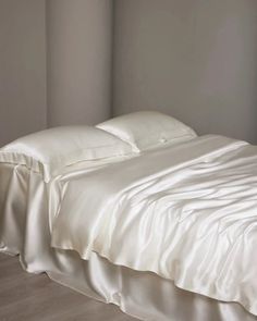 an unmade bed with white sheets and pillows