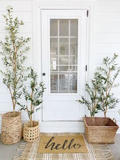 three potted trees sitting next to a door with the word hello written on it