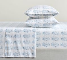 two pillows on top of a bed with blue and white floral print sheets in the foreground