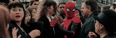 a group of people standing next to each other in front of a spider man mask