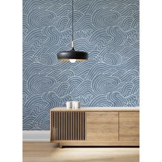 a blue wallpaper with waves on it and a black lamp hanging from the ceiling