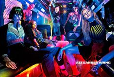 a group of young women sitting on top of a couch in front of neon lights