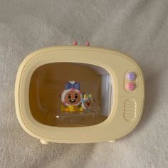 a yellow toy microwave oven sitting on top of a white blanket