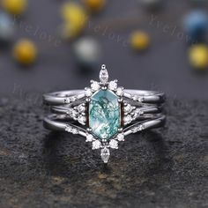 a close up view of a ring with an aqua green stone surrounded by white diamonds