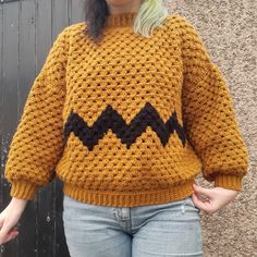 a woman wearing a yellow sweater with black chevrons