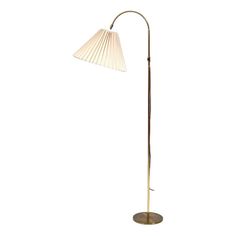 a floor lamp with a white shade on the top and a gold metal base,