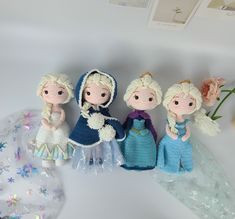 four crocheted dolls sitting next to each other on top of a white table