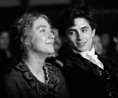 the young man and woman are posing for a black and white photo in front of an audience