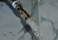 a faucet with water coming out of it sitting on a marble counter top