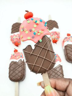 a hand holding an ice cream cone with sprinkles and chocolate on it