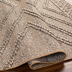 a close up view of a rug on a wooden floor with the end of it laying down