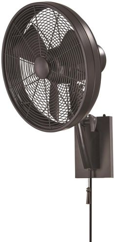 a black wall mounted fan sitting on top of a metal stand next to a light