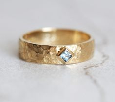 a gold wedding band with a blue diamond in the center