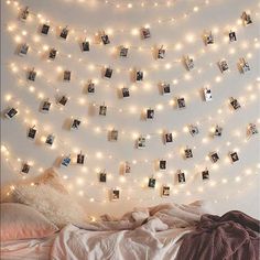 a bedroom with lights strung from the ceiling and pictures on the wall above the bed