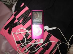 an ipod sitting on top of a pink and black blanket next to headphones attached to it