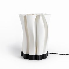 a white vase with black stripes on the sides and a cord in front of it