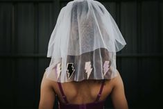 the back of a woman wearing a veil over her head with lightning stickers on it