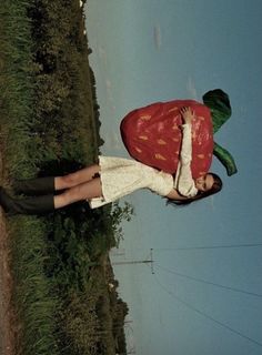 a woman standing in the grass wearing a strawberry costume