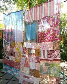 several colorful pieces of cloth hanging on a clothes line in front of some trees and bushes