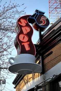 a neon sign for a coffee shop hanging from the side of a building