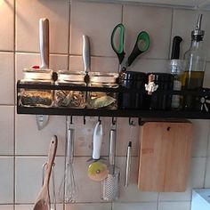 kitchen utensils hanging on the wall above pots and pans with wooden spoons