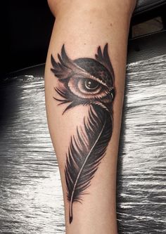 an owl tattoo with a feather on it's leg and the eye is visible