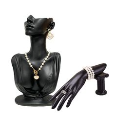 a black mannequin with pearls and jewelry on it's head next to a pair of gloves