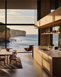 a dining room and kitchen area with large windows overlooking the ocean