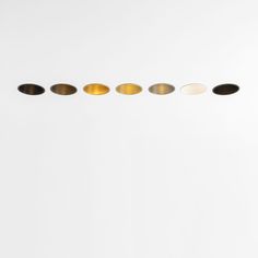 five oval shaped objects are lined up in a row on a white surface, with one yellow and the other black