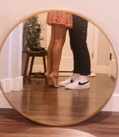 two people standing in front of a mirror with their feet on each other's legs