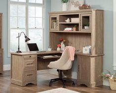 a wooden desk with a computer on top of it next to a chair in front of a window