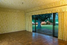 an empty room with sliding glass doors leading to a large tree in the middle of it