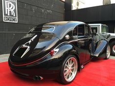 an old black car parked on top of a red carpet