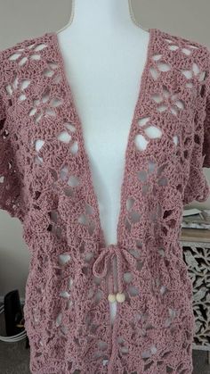 a pink crocheted cardigan on a mannequin