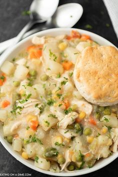 a white bowl filled with chicken pot pie soup and a biscuit on the side