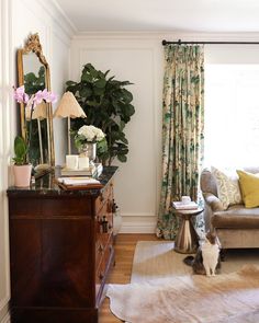 a living room filled with furniture and a cat sitting on top of a wooden dresser