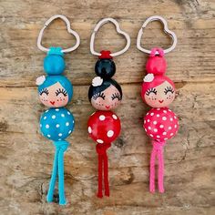 three little doll keychains with hearts and polka dots on them, hanging from hooks