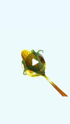 a corn on the cob is being held by a wooden spoon with a green ribbon