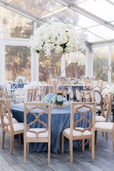 a dining room set up with blue linens and white flowers