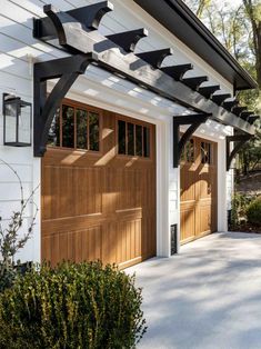 a white house with two brown garage doors and an awning over the front door