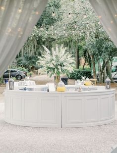 a white table sitting under a canopy next to trees